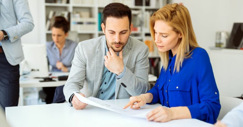 Man and woman reviewing paper document in work environment