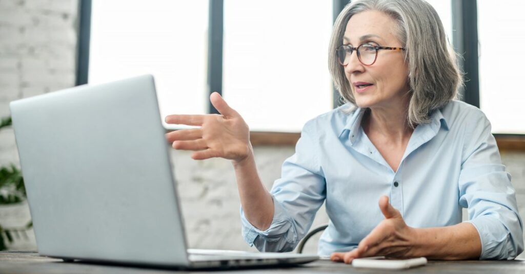 Middle-aged woman wearing glasses looking at a laptop